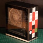 A compact 4.5-liter Framework Desktop showcasing its modular front tiles and clear side panel with a Noctua fan.