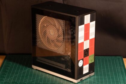 A compact 4.5-liter Framework Desktop showcasing its modular front tiles and clear side panel with a Noctua fan.