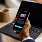 A person using a Windows 11 laptop while their Android smartphone interface is mirrored on the screen via Microsoft Phone Link