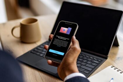 A person using a Windows 11 laptop while their Android smartphone interface is mirrored on the screen via Microsoft Phone Link