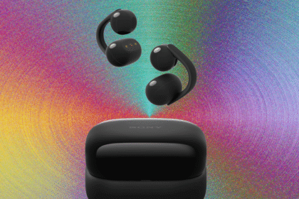 Detailed close-up of the Sony LinkBuds Clip open-ear headphones resting beside their compact, cookie-style charging case on a wooden desk.