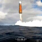 An astronaut aboard the SpaceX Crew-12 capsule holding a modern smartphone to a window to photograph Earth from orbit.