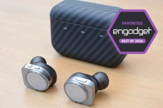 A close-up of a traveler wearing sleek black noise-canceling earbuds while sitting in a crowded, blurred-out international airport terminal.