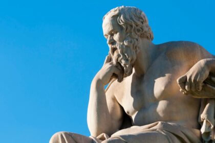 A close-up of a person using a vintage pencil on paper while a glowing holographic AI interface floats nearby in a modern office.