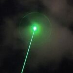 A high-energy LOCUST laser weapon system mounted on a tactical vehicle during a drone defense exercise in a desert setting.