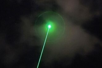 A high-energy LOCUST laser weapon system mounted on a tactical vehicle during a drone defense exercise in a desert setting.