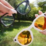 A person wearing stylish Meta Oakley smart glasses while walking through a sunny urban park, capturing 3K video hands-free.
