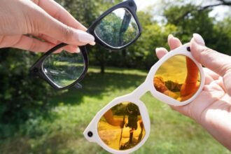 A person wearing stylish Meta Oakley smart glasses while walking through a sunny urban park, capturing 3K video hands-free.