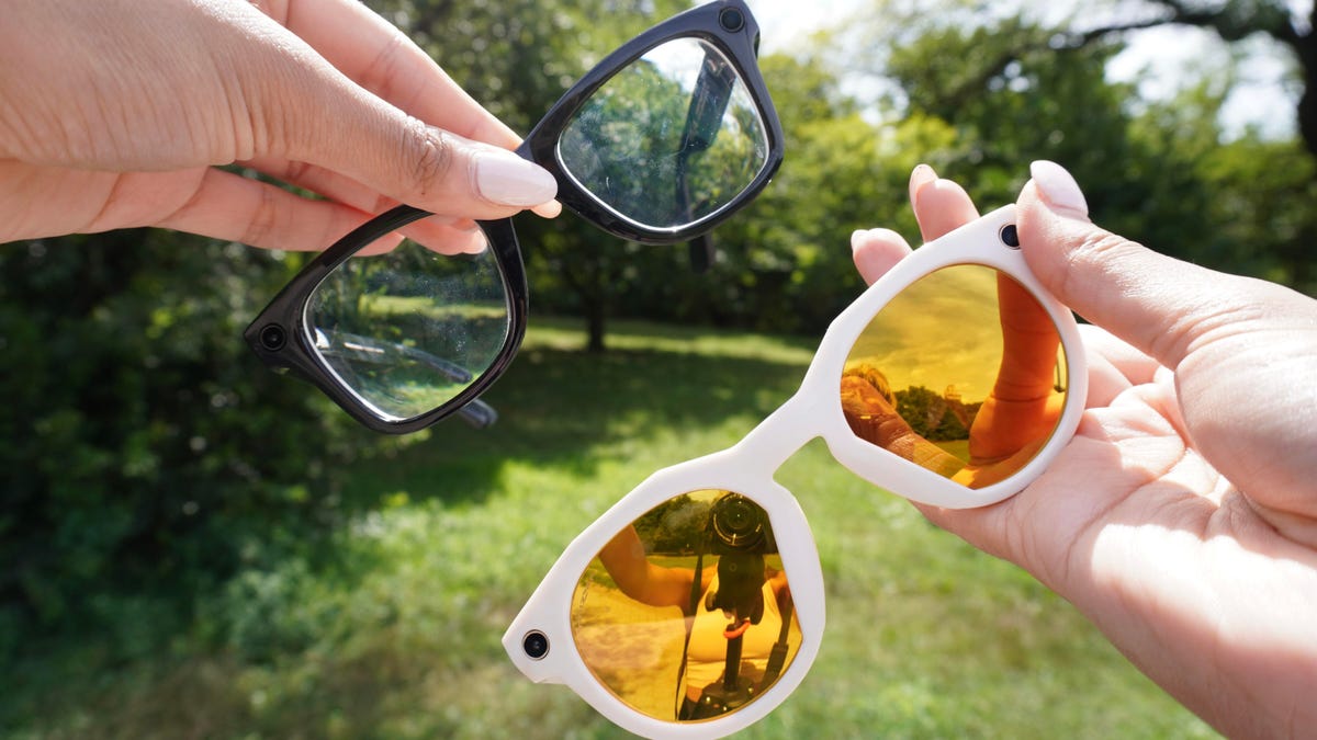 A person wearing stylish Meta Oakley smart glasses while walking through a sunny urban park, capturing 3K video hands-free.