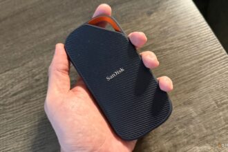 A modern minimalist home office featuring a sleek laptop with a glowing neural network visualization on the screen next to a discarded 2020-era desktop tower.