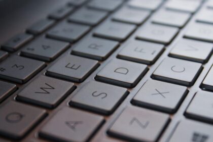 A person sitting in a dimly lit home office, frustratedly typing into a Linux terminal on a Microsoft Surface Pro tablet.