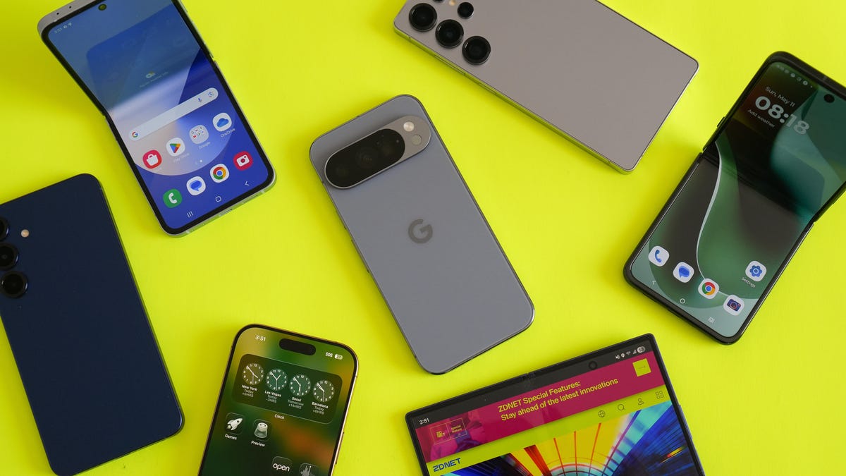 A close-up of the OnePlus 15 and iPhone 17 Pro Max side-by-side on a lab testing bench showing battery percentages.