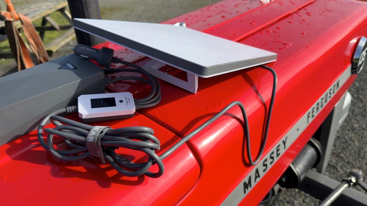 Digital nomad working on a laptop near a camper van with a Starlink Mini dish powered by a USB-C cable.