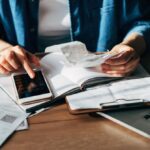 A person using a laptop and smartphone to file taxes through H&R Block DIY online portal in a bright living room