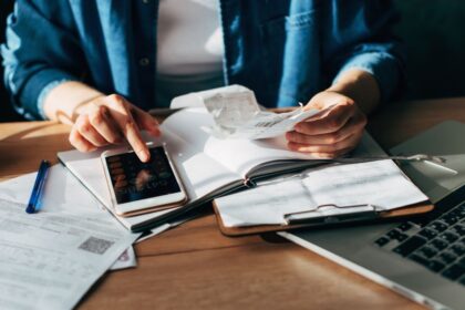 A person using a laptop and smartphone to file taxes through H&R Block DIY online portal in a bright living room