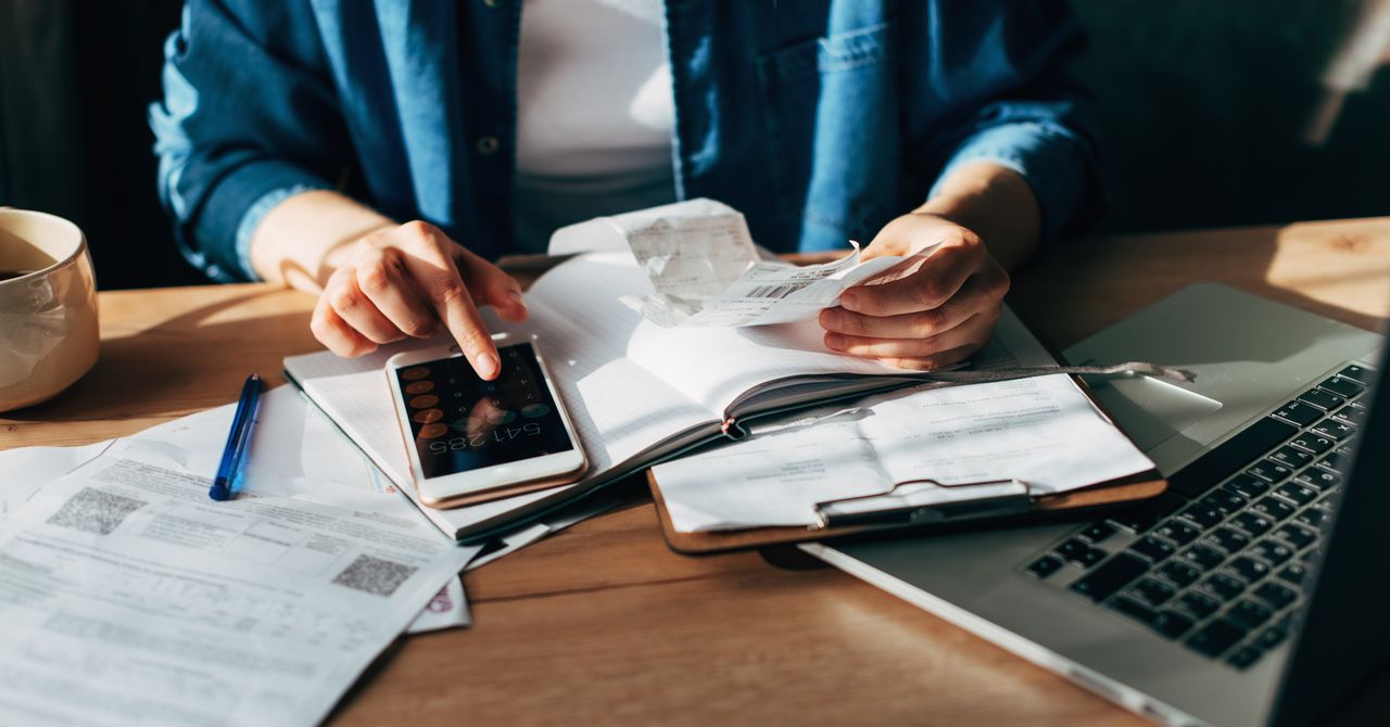 A person using a laptop and smartphone to file taxes through H&R Block DIY online portal in a bright living room