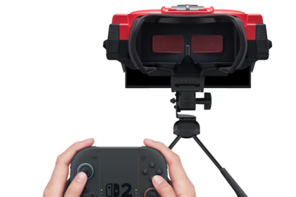 A person using a red and black Nintendo Virtual Boy accessory attached to a Nintendo Switch 2 console on a table.