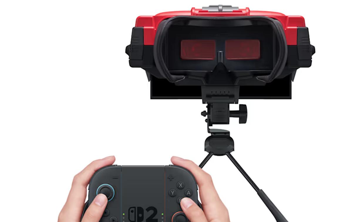 A person using a red and black Nintendo Virtual Boy accessory attached to a Nintendo Switch 2 console on a table.