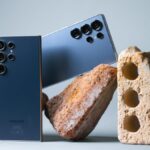 Samsung Galaxy S24 Ultra and S25 Ultra smartphones side-by-side on a wooden desk highlighting titanium frames and S-Pen styluses.