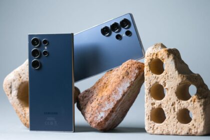 Samsung Galaxy S24 Ultra and S25 Ultra smartphones side-by-side on a wooden desk highlighting titanium frames and S-Pen styluses.