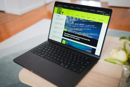 A space black M4 MacBook Pro 14-inch model displaying professional video editing software on a minimalist wooden office desk