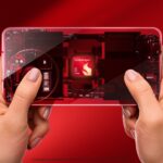 A sleek 2026 flagship smartphone disassembled on a wooden desk, highlighting the Snapdragon 8 Gen 5 chipset and its surrounding thermal cooling system.