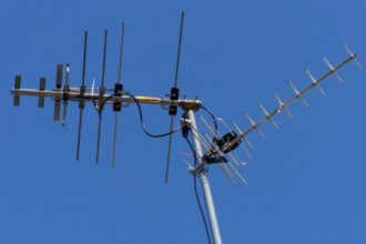 A sleek, modern Mohu Gateway Plus indoor antenna positioned discreetly on a minimalist bookshelf next to a high-end smart TV in a contemporary living room.