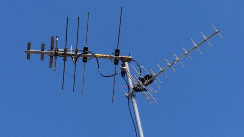 A sleek, modern Mohu Gateway Plus indoor antenna positioned discreetly on a minimalist bookshelf next to a high-end smart TV in a contemporary living room.