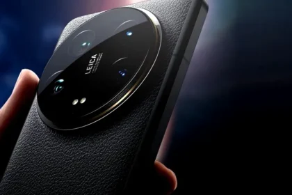 Close-up of a sleek ceramic smartphone camera module with Leica branding resting on a wooden table in a sunlit cafe