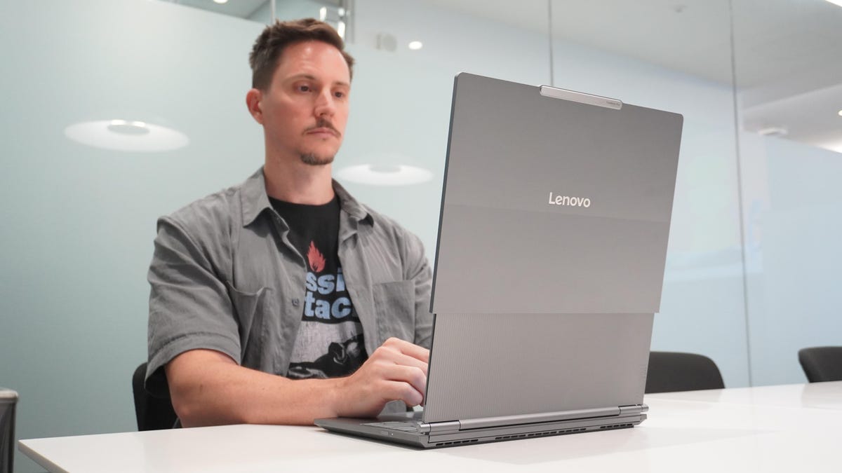 A remote worker smiling at a laptop, experiencing stress-free productivity thanks to Optimum's 300 Mbps fiber internet connection.